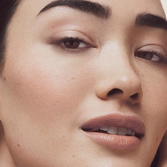 Close up of Vitamin Enriched Face Base with swatch behind over a pale blue background